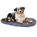 An Aussie lounges on a gray and blue Chuckit Travel Pillow Bed. Its fluffy tricolor coat and tongue out, the dog is adventure-ready. The machine-washable mat offers easy care for pet owners on the go.