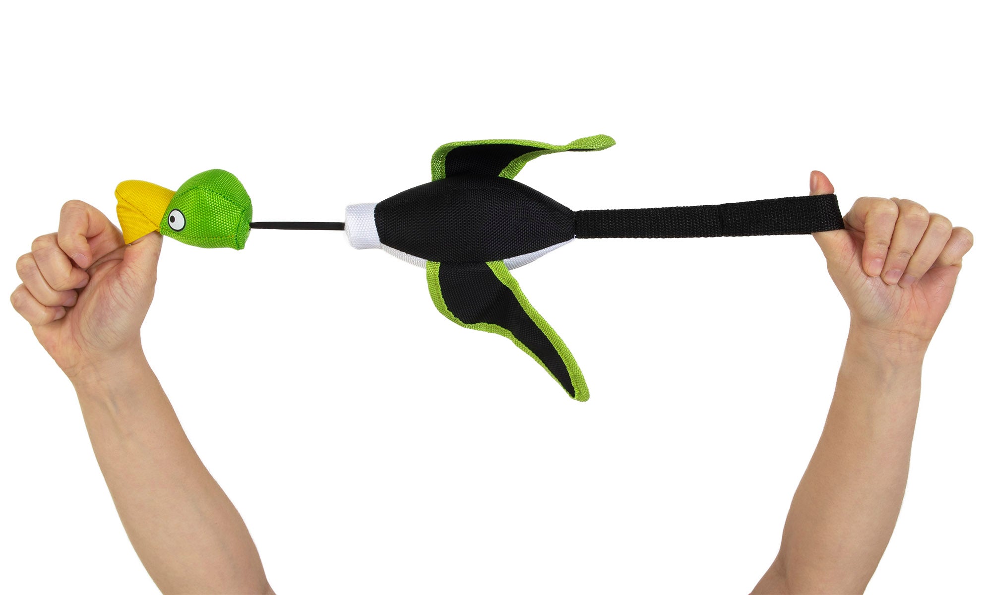 Two hands stretch a Hyper Pet Mini Flying Duck Green Dog Toy, featuring wings and a yellow beak. The left hand grips the head while the right pulls the tail, hinting at slingshot-style play. Made by Hyperpet from non-toxic vinyl, it’s safe and fun to launch.