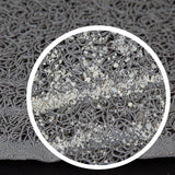 A close-up of a textured tan mat, likely the Petmate Paws Large Litter Catcher Mat, features a circular zoom-in showing intricate tangled loops. The soft rubberized material is BPA and phthalate-free, with small white particles scattered over the loops, emphasizing the detailed pattern.