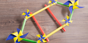 Colorful DNA model made of foam tubes and pinwheels, placed on a wooden surface