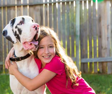 Young girl hugging her dog in her backyard