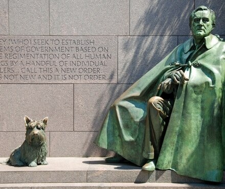 A dog sitting in front of a monument