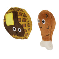 The Mad Cat Chicken and Waffles Twin Pack Catnip & Silvervine Cat Toy features plush toys shaped like a smiling waffle with butter and a chicken drumstick, both with large eyes. The waffle is round with a grid pattern, and the drumstick has a white bone end—perfect for playful cats.