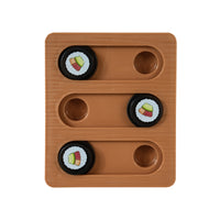 The Quirky Kitty Sushi Bento Box Puzzle Cat Toy features a brown wooden board with three sliding tracks and four black circular pieces, each adorned with a cupcake design. Two tracks contain two pieces, while one track is left empty to challenge feline cognition.