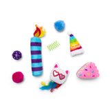 The Quirky Kitty Birthday Box 8pk by Quirky Kitty features colorful cat birthday toys like a striped candle, fuzzy balls, spring, party hat, pink frosted cake slice, and a white cat face with heart glasses and feathers.