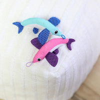 The Quirky Kitty Flying Fish 2pk—Interactive Catnip Cat Toys with Slingshot—features a blue and a pink fish, each with purple fins, large stitched eyes, and looped mouths on a white textured surface.