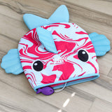 The Quirky Kitty Fish Cooling Mat – Ocean-Themed Cat Play Mat by Quirky Kitty features a red and white swirled fish design, blue fins, cartoon eyes, and a small attached purple toy—perfect for keeping cats cool on any wooden floor.