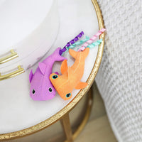 The Quirky Kitty Color Changing Shark 2pk—ocean-themed catnip toys—features two vibrant shark designs on a white and gold table, making them perfect interactive toys for playful felines.