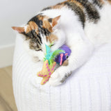 A calico cat lounges on a white cushion, playfully hugging and biting Quirky Kitty Pufferfish Pals Cat Toys 2-Pack—cooling catnip ocean toys by Quirky Kitty.