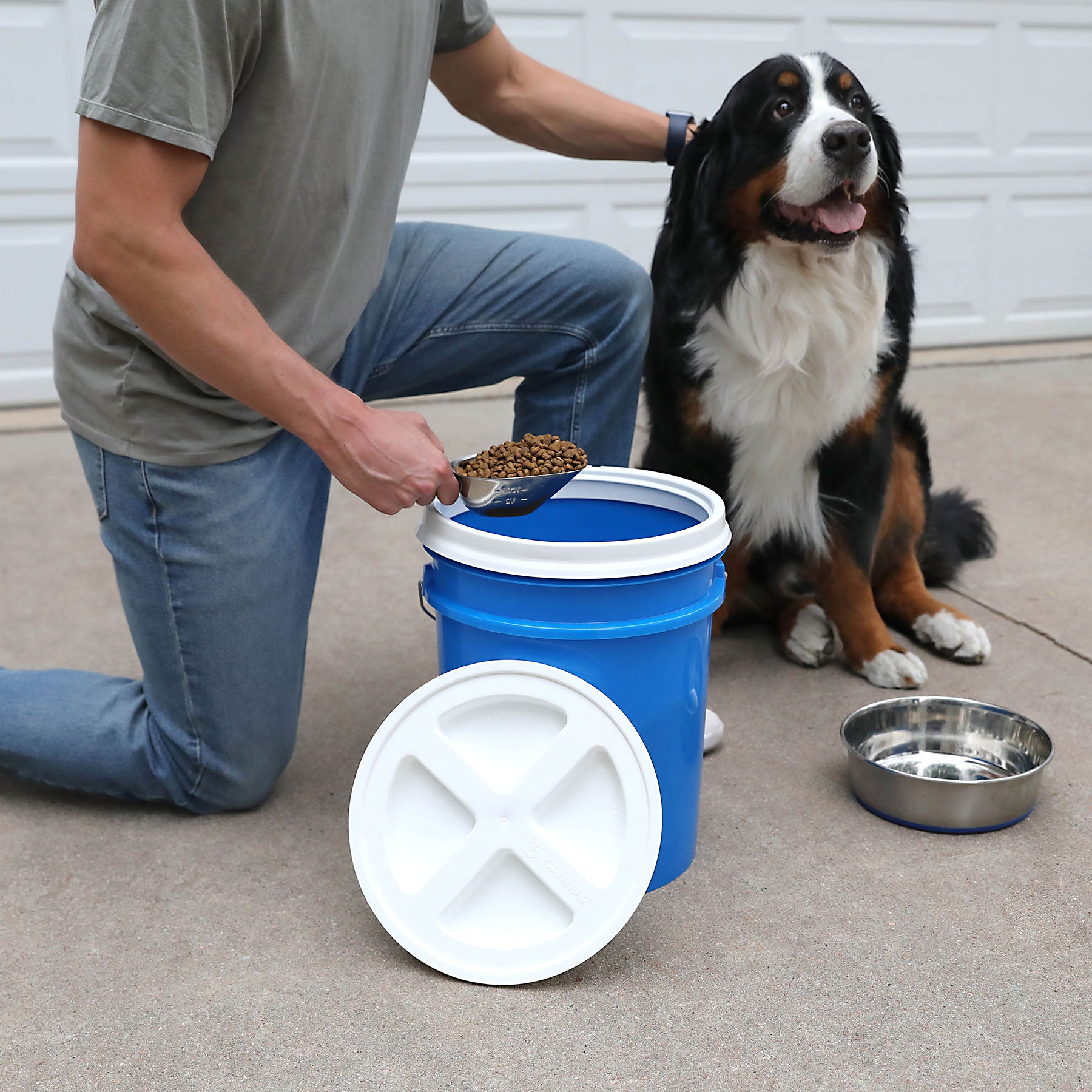 A man uses the Vittles Vault 2.0 Replacement Lid to carefully portion kibble, keeping it fresh and delighting his dog with perfect servings every time.