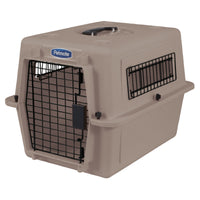 The Petmate Ultra Vari Kennel is beige with a black wire door and side vents. The slightly open door shows a Petmate label near the top, and theres a handle for easy transport.