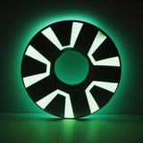 The Chuckit! Zipflight Max Glow Dog Toy, by Chuckit, is a circular object resembling a futuristic disc with glowing green and black segments that radiate light on a dark background.