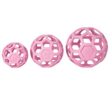 Three pink JW Hol-EE Roller Trend-EE puzzle balls of varying sizes, made from natural rubber with a hexagonal lattice design, are lined up in ascending order from left to right. Each ball provides mental stimulation for dogs and features JW embossed on a panel.