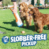 Using the Chuckit! Cannon & Cannon Max Dog Ball Launcher by Chuckit!, someone picks up a ball from the grass while two brown dogs watch. "Slobber-Free Pickup" and a crossed-out slobbering dog logo appear on the image.