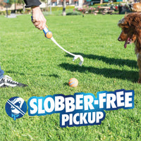 Using the Chuckit! Ultra Ball Launcher 18" Medium with included tennis ball, a person picks up a ball from the grass as a brown dog looks on. Text reads "Slobber-Free Pickup" with an icon of a crossed-out slobbering mouth.
