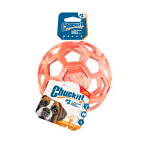 An orange Chuckit! Hol-ee Roller interactive dog toy ball in packaging displays a dog photo, Chuckit! brand logo, and product info with icons showing fetch, tug, and treat-stuffing play.
