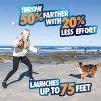 On a sandy beach, a woman uses the Chuckit! Ultra Launcher with Ultra Ball 18M by Chuckit! to throw a ball for her dog. Bold text: Throw 50% farther with 20% less effort—launches up to 75 feet. Ocean waves and rocks in the background.