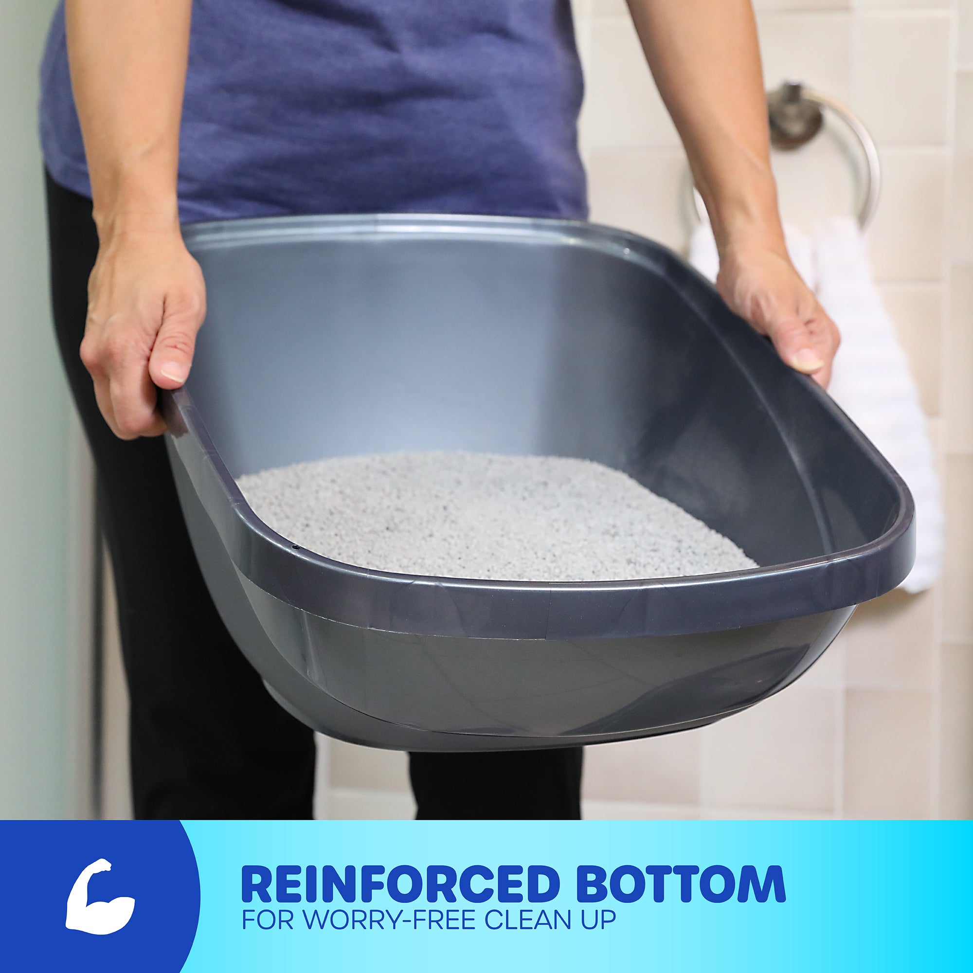 A person holds a gray Petmate Hi-Back Open Litter Box filled with cat litter. Text at the bottom states REINFORCED BOTTOM FOR WORRY-FREE CLEAN UP alongside a flexing arm icon.
