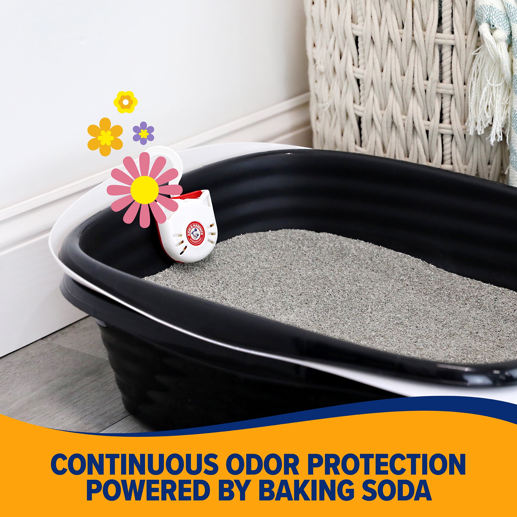 A black litter box with gray litter includes a small device featuring a cat face design. Set against white walls and near a wicker basket, it offers Continuous odor protection powered by Arm & Hammer Purifying Pak Cat Litter Deodorizer from Arm And Hammer.
