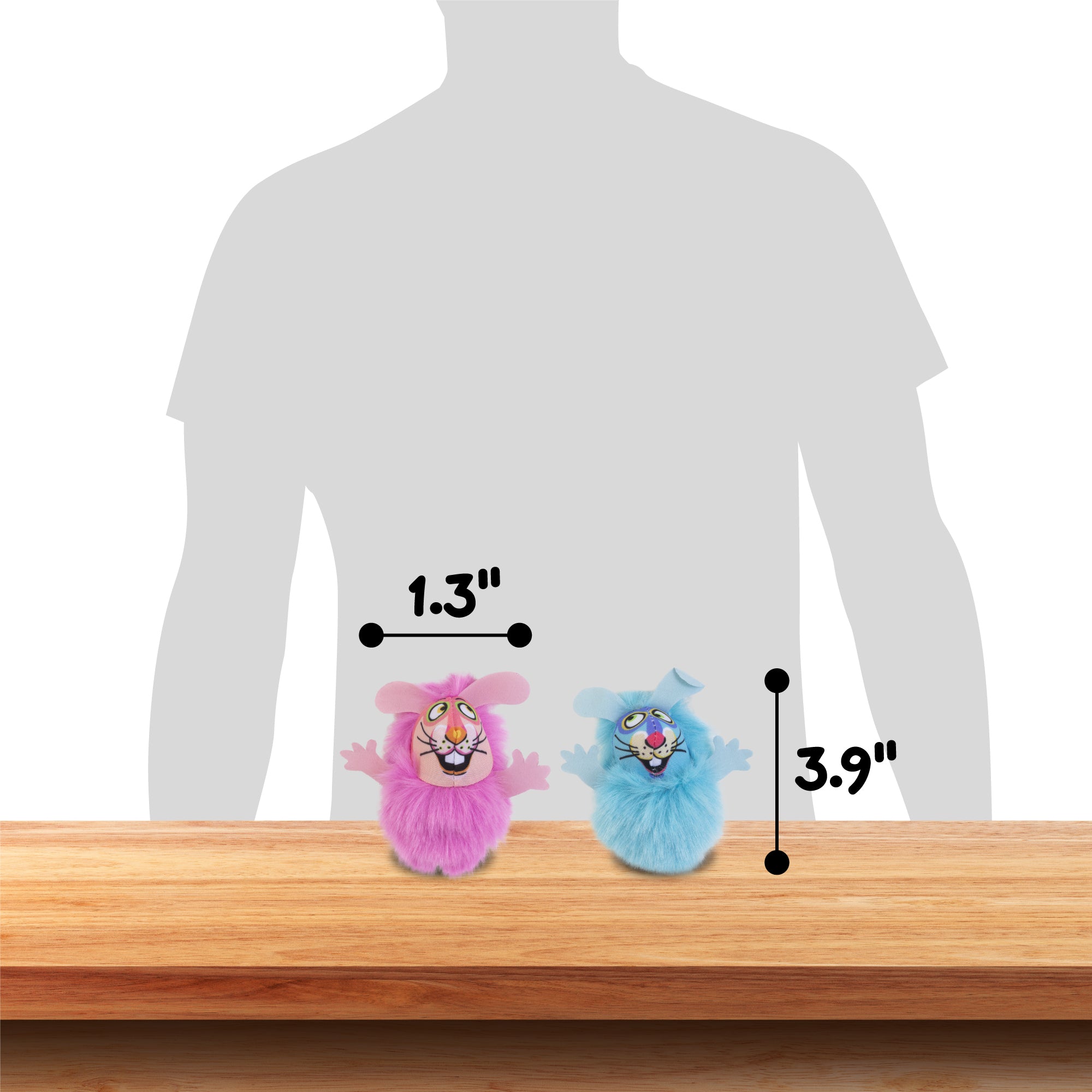 Two small, colorful toy creatures sit on a wooden surface. The pink one is 1.3 inches tall, and the blue stands at 3.9 inches. Modeled after Fatcats FAT CAT Classic Fluff Bunnies Cat Toy, they are posed in front of a silhouette for size reference, ready to zoom around in playful adventures.