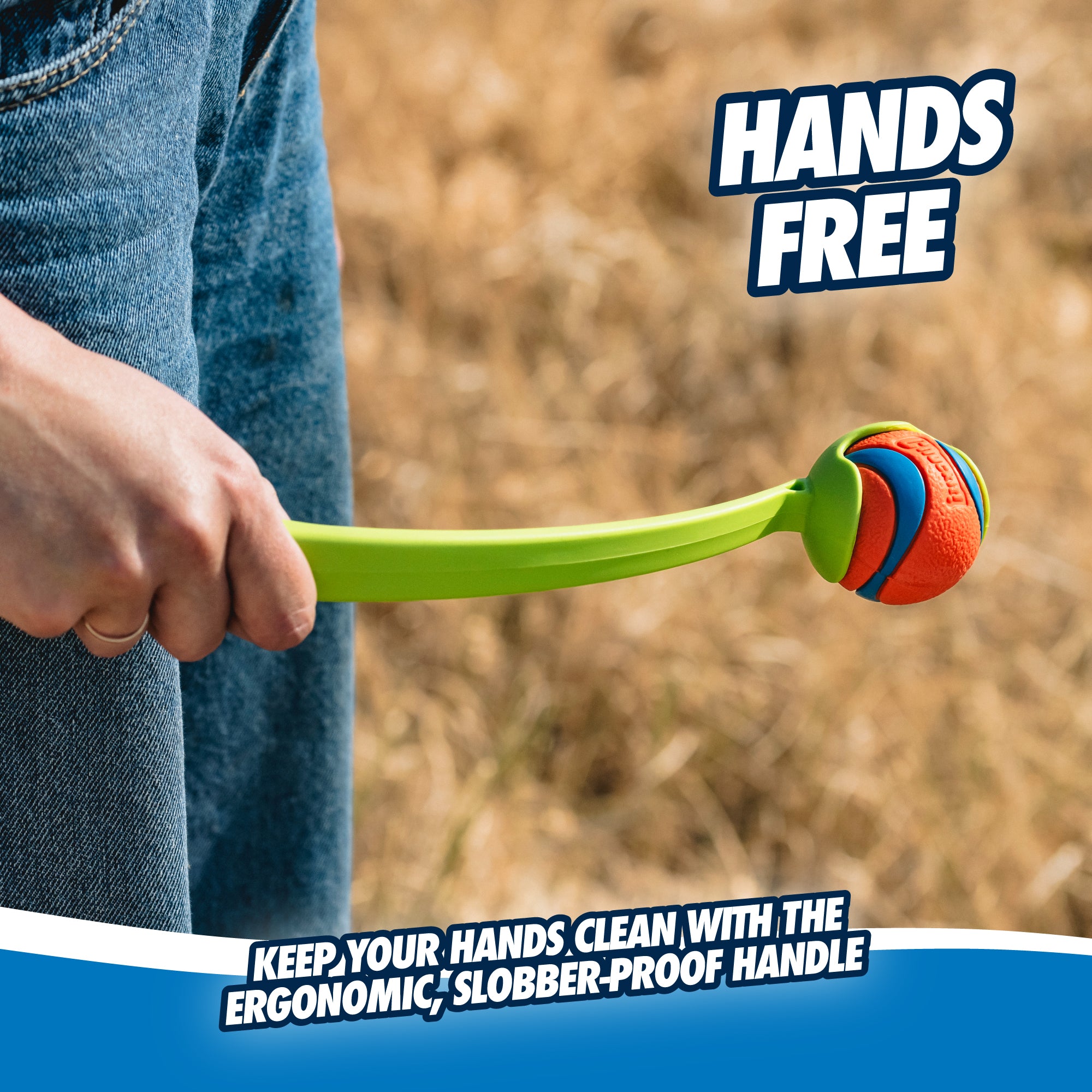 A person holds a Chuckit! Sport Launcher with a vibrant rubber ball, ideal for hands-free play. On dry grass, the image displays Hands Free and Keep your hands clean with the ergonomic, slobber-proof handle, guaranteeing easy, hands-free pickup with this clever Chuckit design.