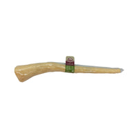 The Wild Eats 11 Water Buffalo Tail Dog Chew by Wild Eats is a large, light beige bone-shaped dog chew wrapped in clear plastic. A small green and beige label near one end highlights its dental health benefits, and it is made from natural water buffalo. The product is set against a white background.