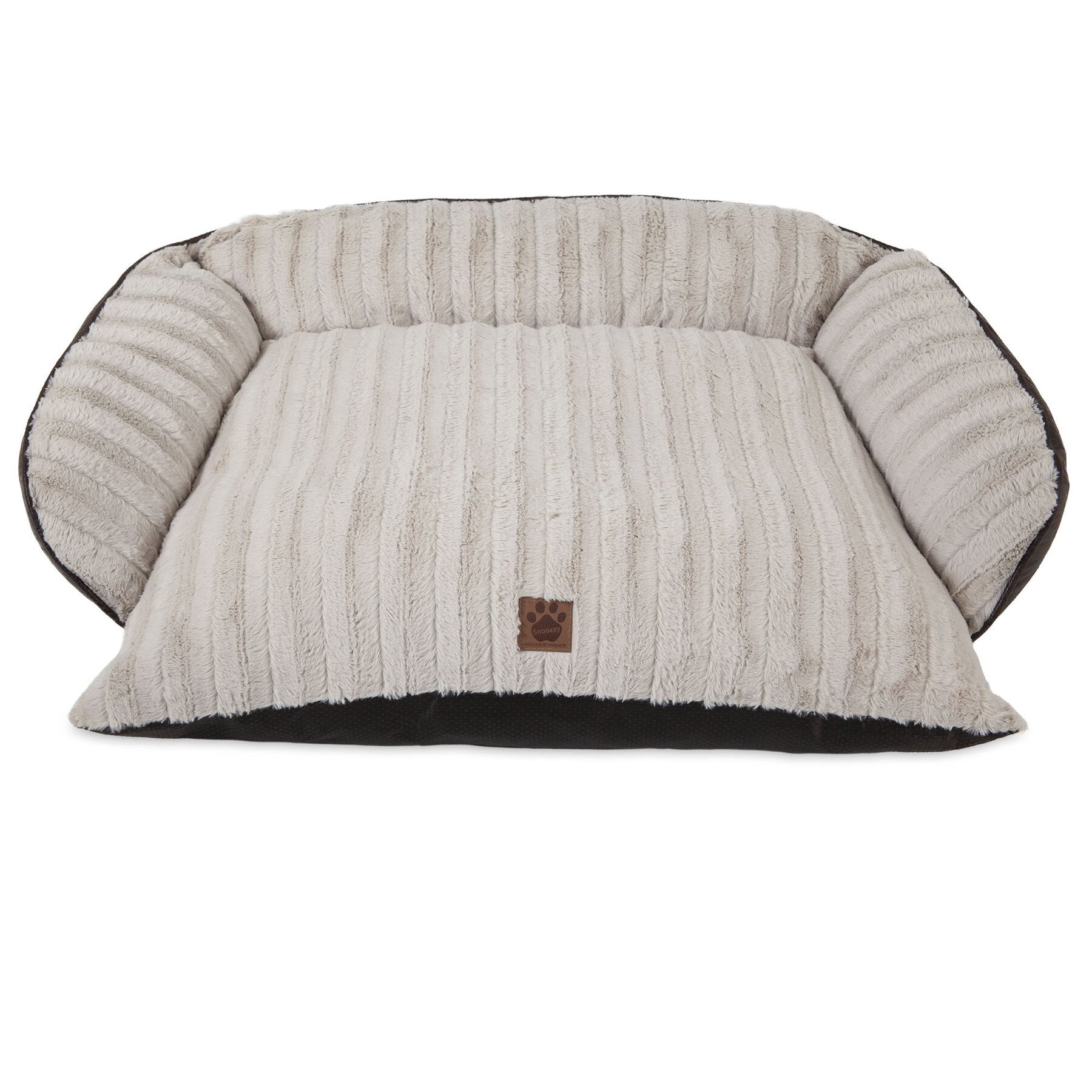 The Snoozzy Rustic Luxury Comfy Couch Pet Bed is plush and cream-colored, featuring ribbed fabric and raised sides. A small brown tag with a paw print decorates the front. Its machine washable for easy care, shown empty against a plain white background.