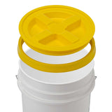 A white HDPE bucket, BPA-free, features a yellow Gamma Seal Lid from Gamma2 with a cross-shaped indentation for an airtight seal. The lid is positioned above the bucket, ready to attach. A sturdy metal handle completes the design.