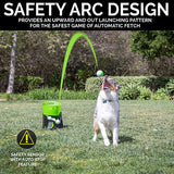 In a grassy yard, a dog observes the Hyperpet GoDogGo Fetch Machine Dog Ball Launcher as it propels a ball. Featuring SAFETY ARC DESIGN for an upward trajectory and an Auto Stop Feature with caution symbol, this ensures fun and safe interactive playtime.