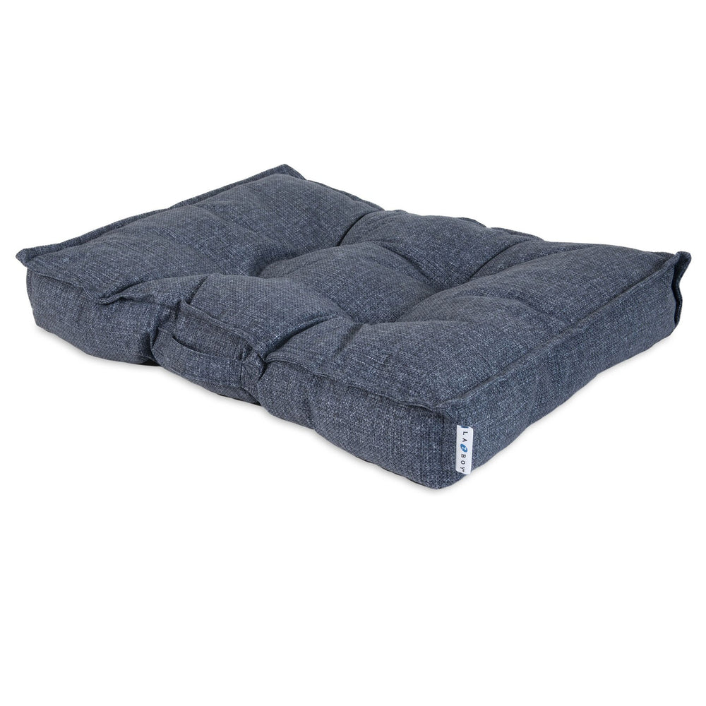 A dark blue, tufted rectangular cushion with textured fabric and raised edges lies on a white background, resembling the La-Z-Boy Outdoor Millie Mattress Dog Beds luxurious style. A small tag adds detail to its cozy allure.