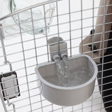 The Petmate No Spill Kennel Cup by Petmate is a gray automatic water dispenser attached to a metal cage, featuring a transparent bottle and dual spouts for spill-proof travel convenience.